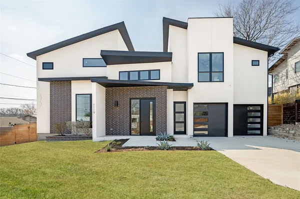 a view of a house with large windows and a small yard