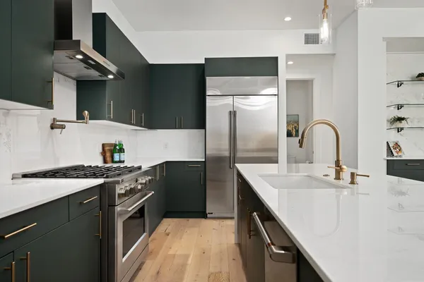 a kitchen with stainless steel appliances granite countertop a sink a stove and a refrigerator