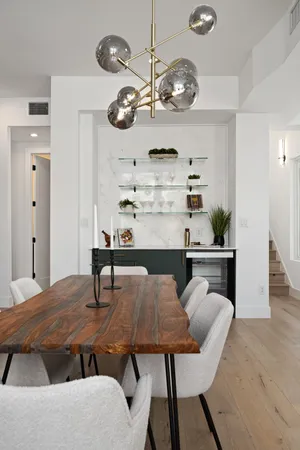 a dining room with wooden floor a chandelier fan a wooden table and chairs