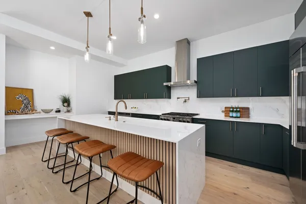 a kitchen with stainless steel appliances a stove a sink a microwave a dining table and chairs with wooden floor