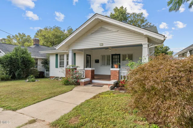 a front view of a house with a yard and potted plants
