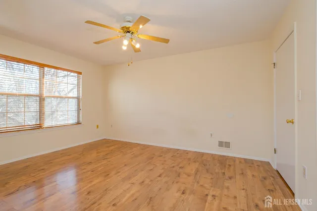 an empty room with a chandelier fan and windows