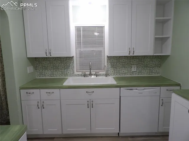 a kitchen with white cabinets and sink
