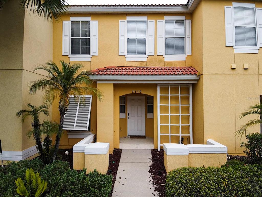 a view of brick house with a large windows and plants
