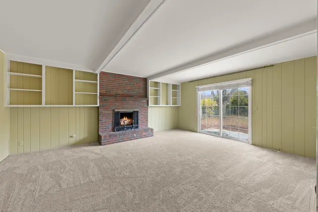 a view of an empty room with a window and fireplace