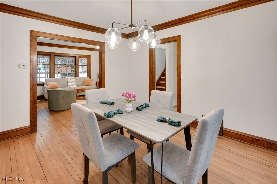 2016 Rossmoor Road Cleveland Heights, OH 44118 - Photo 16 of 46 Dining space featuring crown molding, light wood-style flooring, a chandelier, and stairway