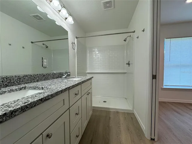a bathroom with a granite countertop sink a large mirror and a shower