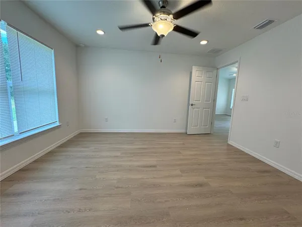 an empty room with a ceiling fan and window
