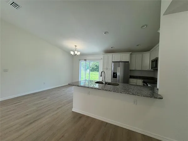 an empty room with a kitchen stove a sink and a window