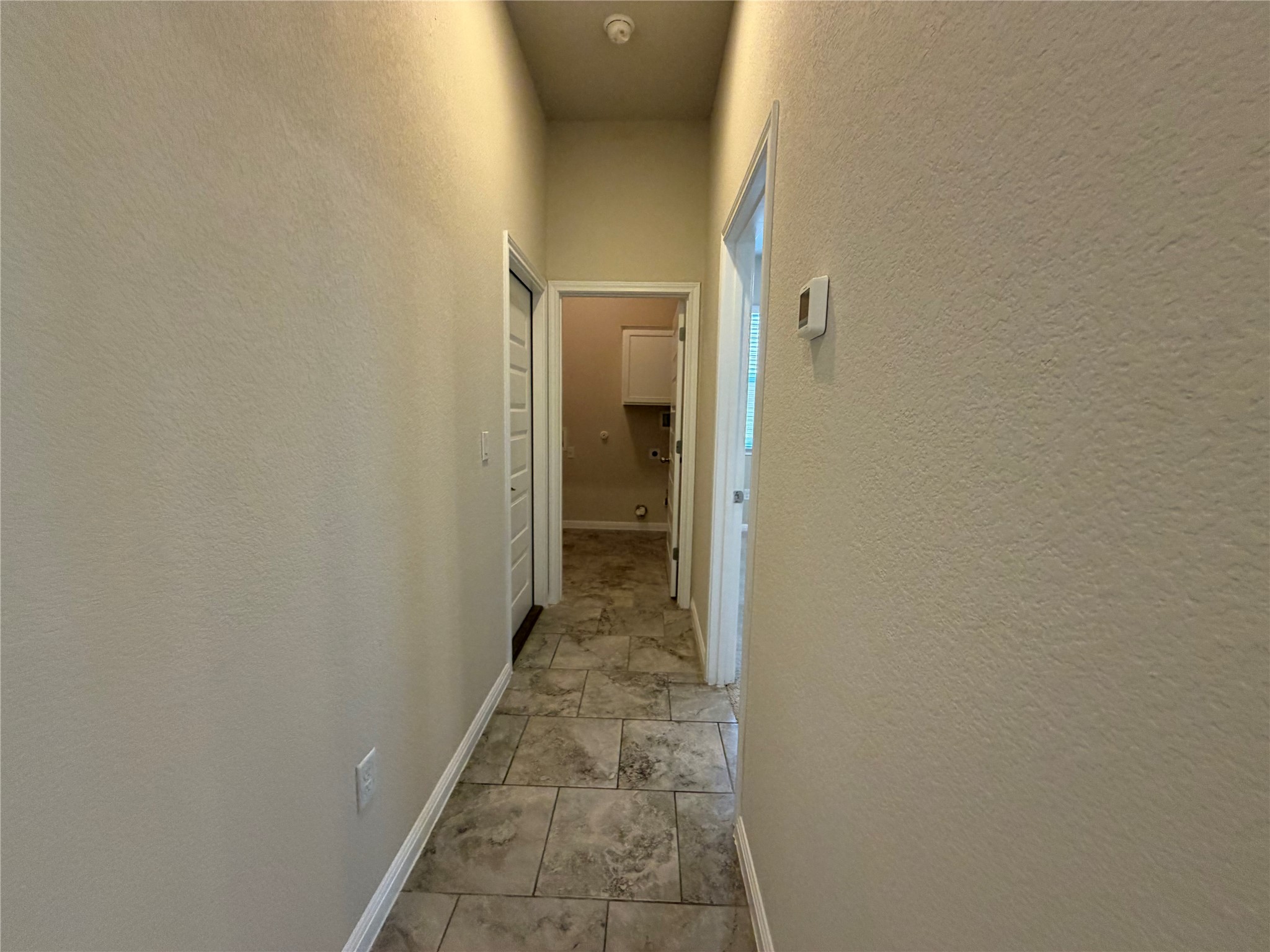 419 Gettysburg Loop Elgin, TX 78621 - Photo 11 of 21 A well-lit corridor with durable tile flooring leads to functional interior spaces.