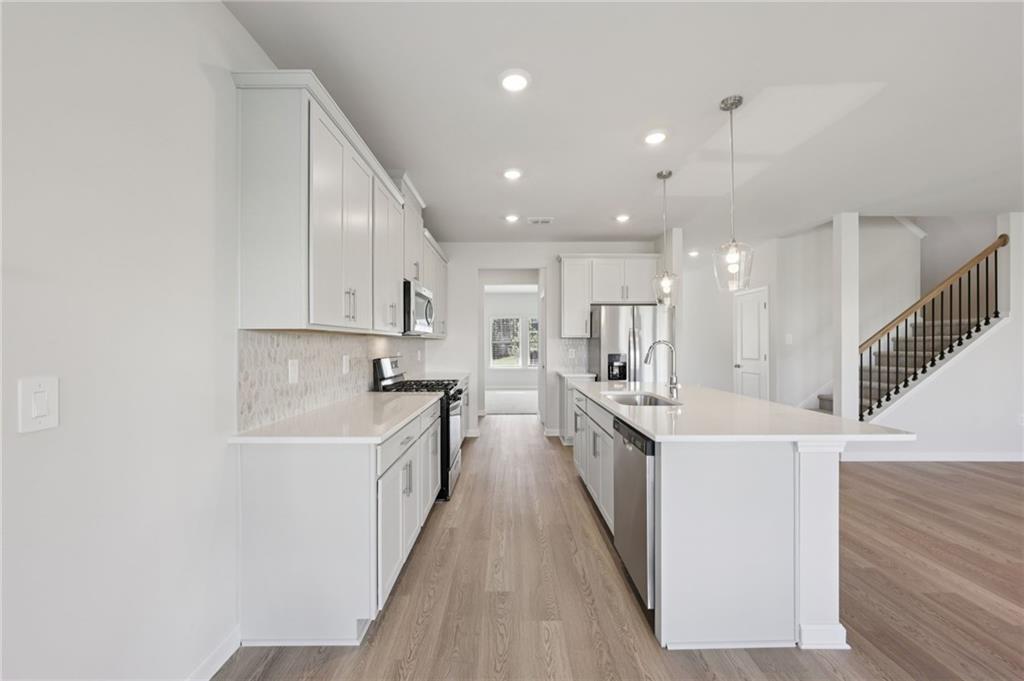 1489 High Fls Lane Grayson, GA 30017 - Photo 13 of 44 a large white kitchen with lots of counter space wooden floor and stainless steel appliances