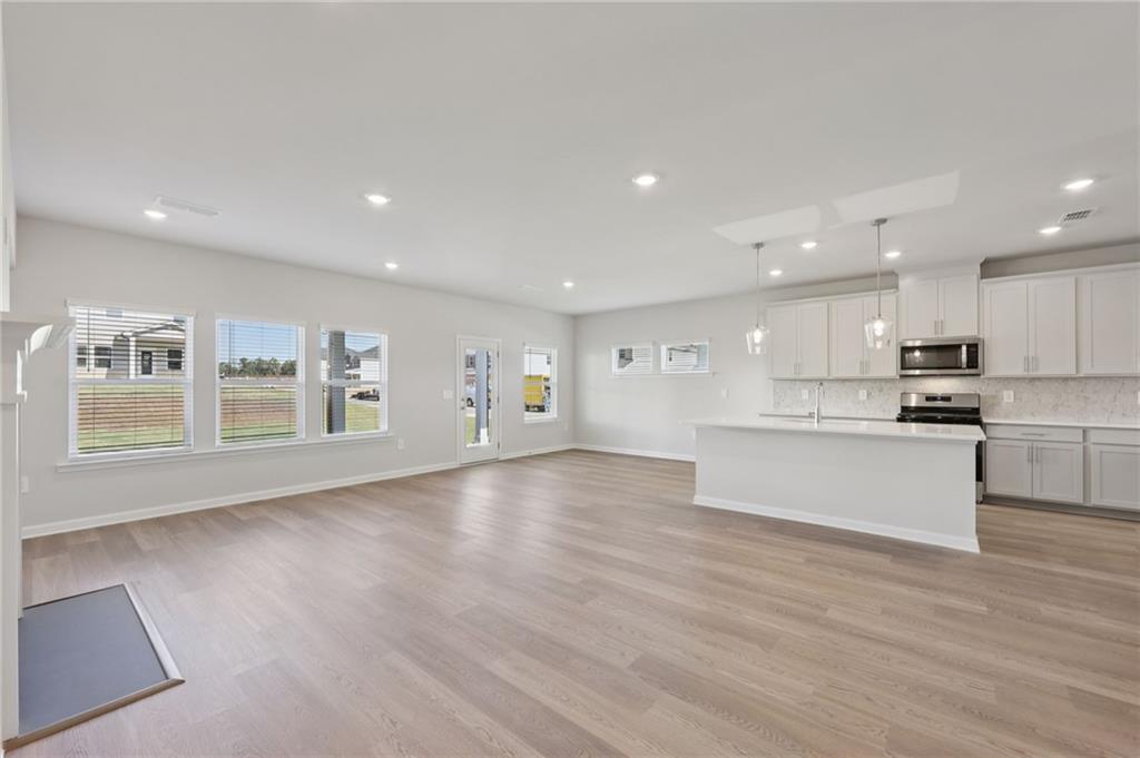 1489 High Fls Lane Grayson, GA 30017 - Photo 7 of 44 a large kitchen with stainless steel appliances kitchen island a large counter top and a wooden floors