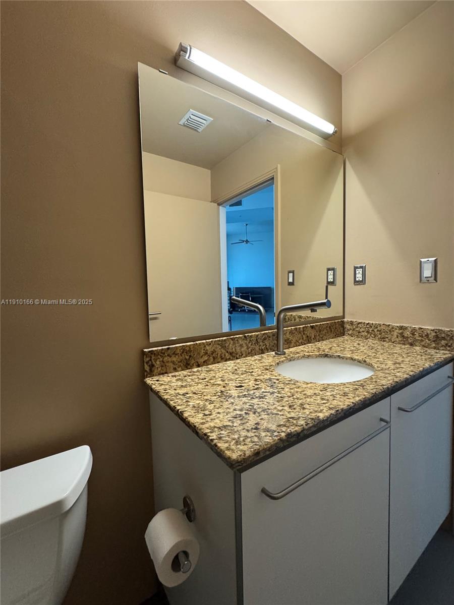 9055 Southwest 73rd Court, Unit 406 Miami, FL 33156 - Photo 10 of 18 a bathroom with a granite countertop sink and a toilet