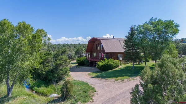 a aerial view of a house with a yard and large trees