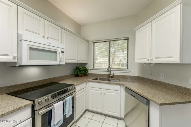 a kitchen with white cabinets and appliances