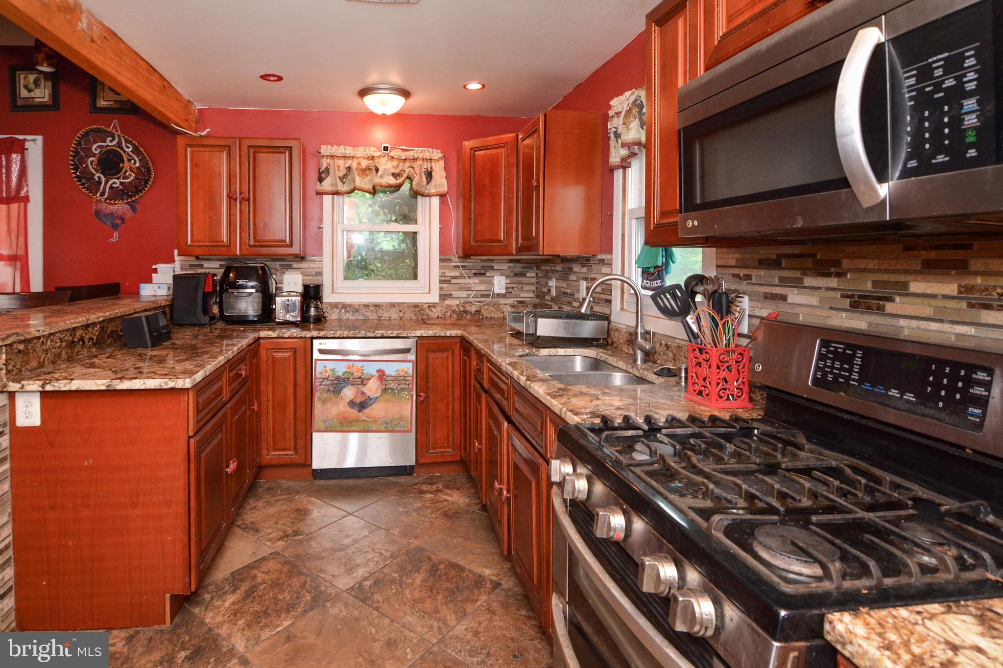 a kitchen with stainless steel appliances granite countertop a stove a sink dishwasher and cabinets with wooden floor