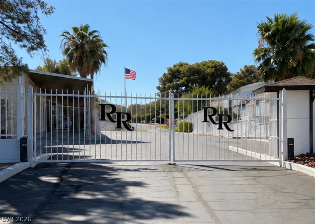 4556 Royal Ridge Way Las Vegas, NV 89103 - Photo 25 of 49 A secure gated entrance stands prominently beneath palm trees and clear blue skies.