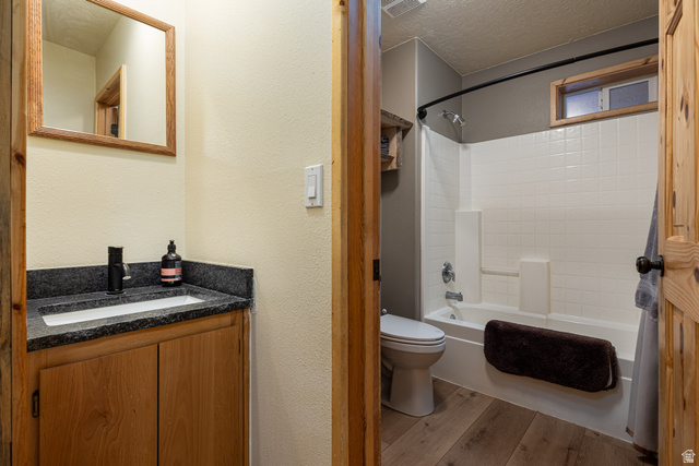 1505 West Elk Ridge Drive Alton, UT 84710 - Photo 32 of 53 Full bath featuring shower / bathtub combination with curtain, wood finished floors, vanity, a textured ceiling, and a textured wall