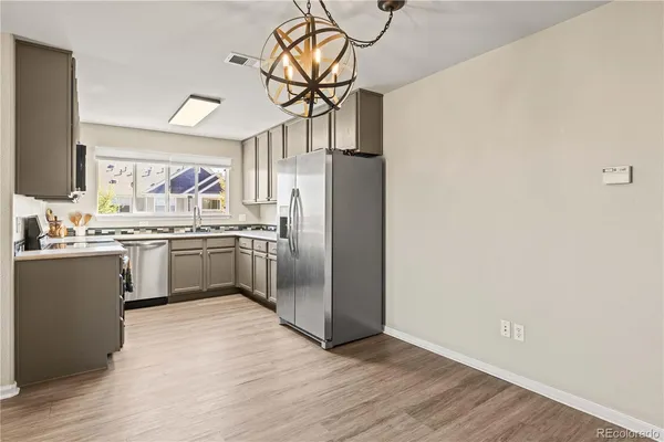 a kitchen with stainless steel appliances granite countertop a refrigerator a sink a stove and white cabinets with wooden floor