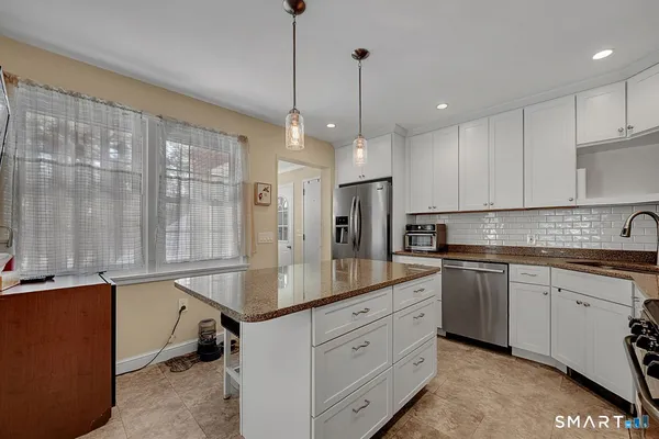 a kitchen with stainless steel appliances granite countertop a sink a center island and cabinets