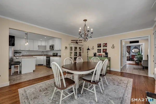 a dining room with wooden floor a chandelier a wooden table and chairs