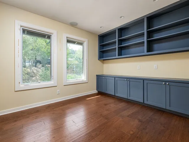 a view of an empty room with wooden floor and windows