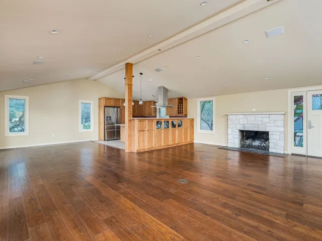 a view of a livingroom with furniture a fireplace wooden floor and windows