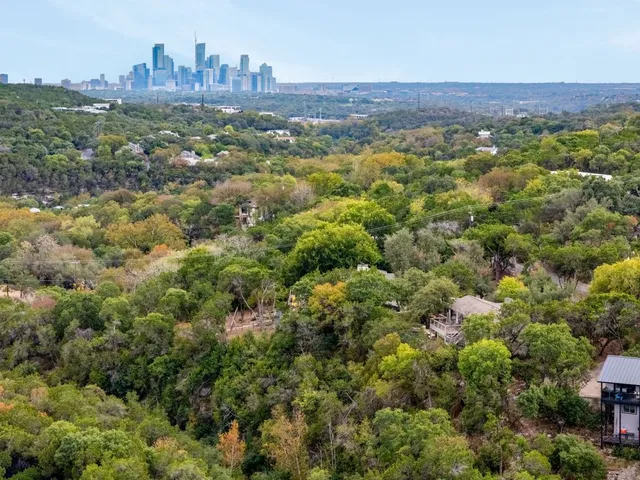 an aerial view of residential houses with outdoor space and trees