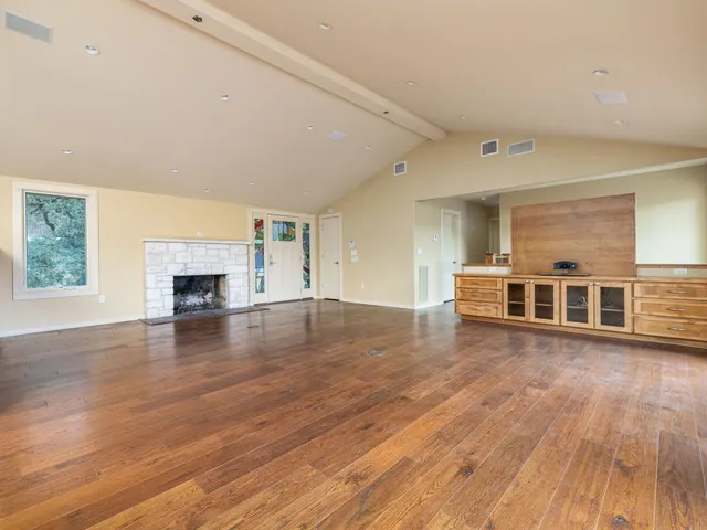 an empty room with wooden floor and fireplace