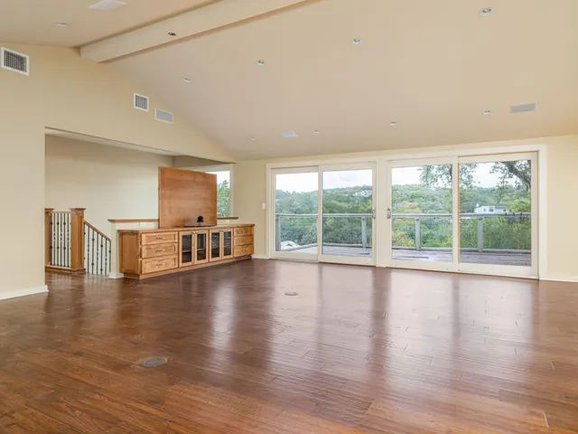 a view of empty room with wooden floor and floor to ceiling window