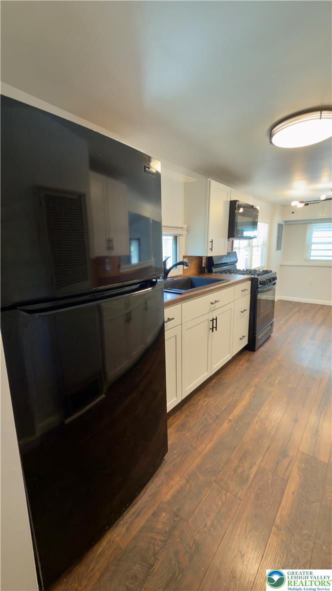 246 Poplar Street Bath, PA 18014 - Photo 23 of 34 A well-equipped kitchen features dark appliances contrasting with white cabinetry and warm wood flooring.