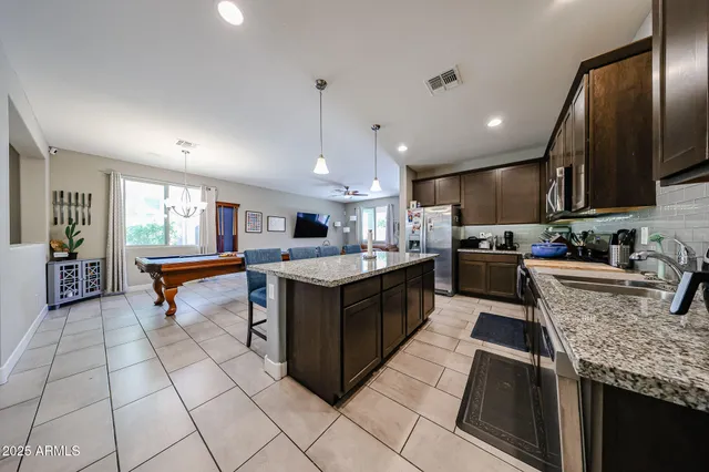 a kitchen with stainless steel appliances granite countertop a dining table chairs refrigerator and microwave