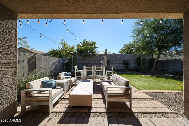 a view of a backyard with table and chairs potted plants and a large tree