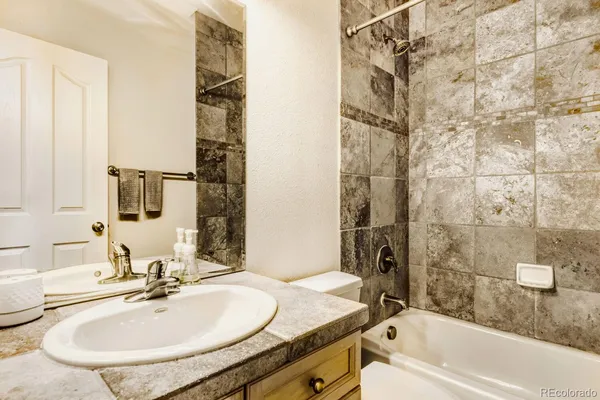a bathroom with a granite countertop sink a mirror a bathtub and shower