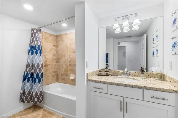 a bathroom with a granite countertop sink a mirror a vanity and a shower