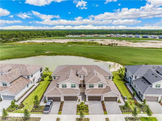 a front view of a house with a garden and lake view