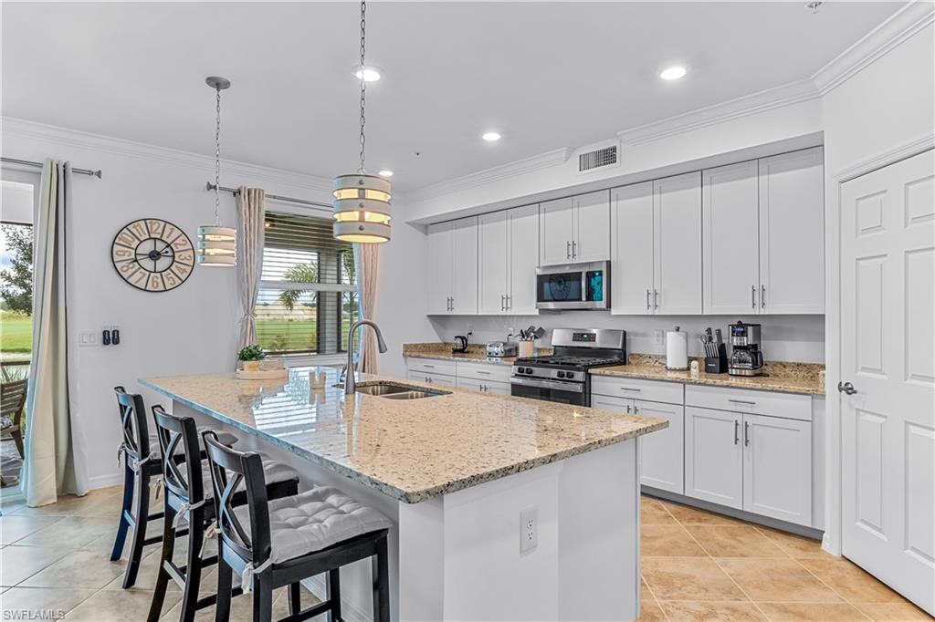 15943 Grassland Lane, Unit 3912 Babcock Ranch, FL 33982 - Photo 7 of 20 a kitchen with a table chairs stove top oven and cabinets