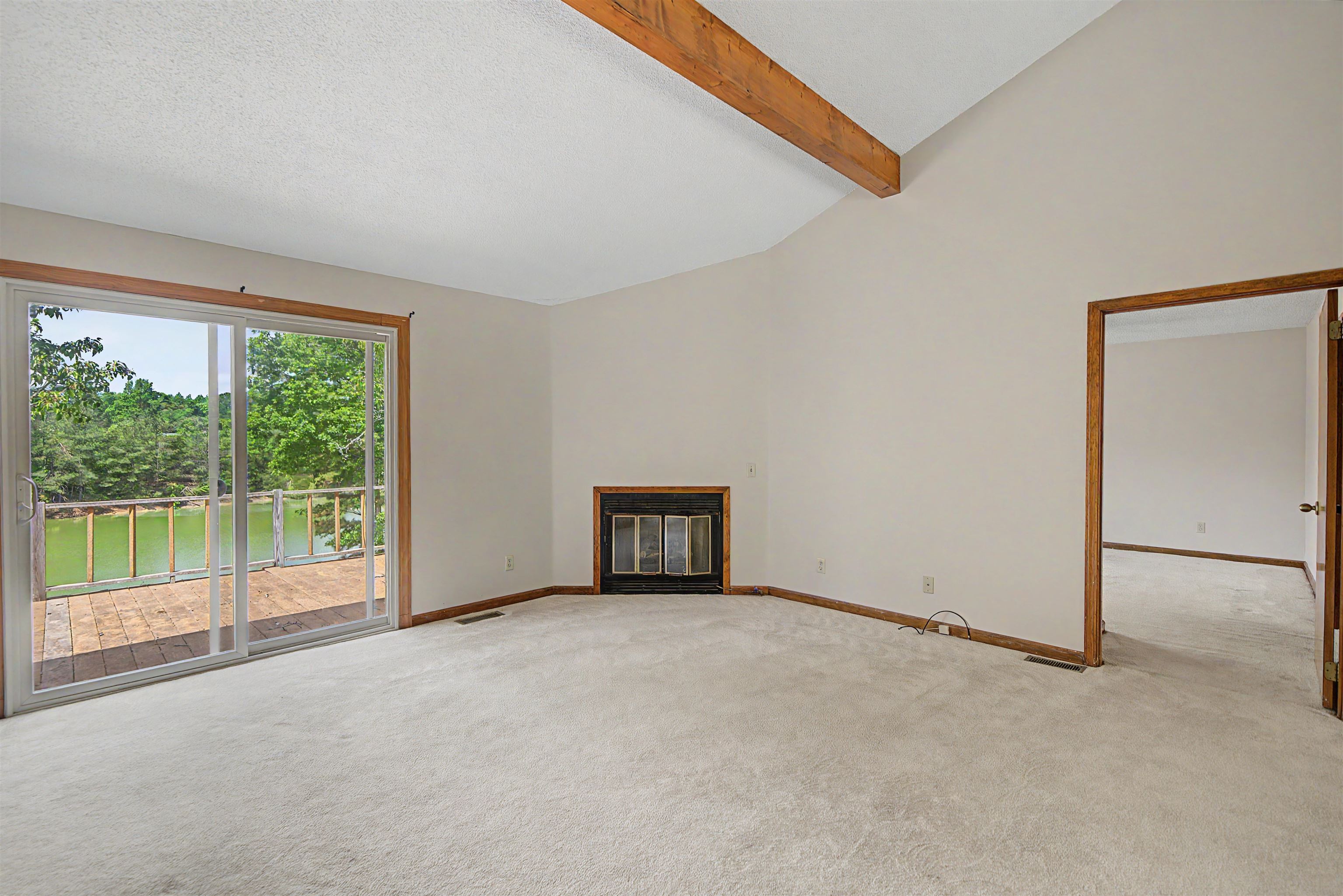 162 Lawton Road Selmer, TN 38375 - Photo 11 of 36 Living area featuring vaulted ceilings with exposed wood beams, a fireplace, and wall-to-wall carpeting