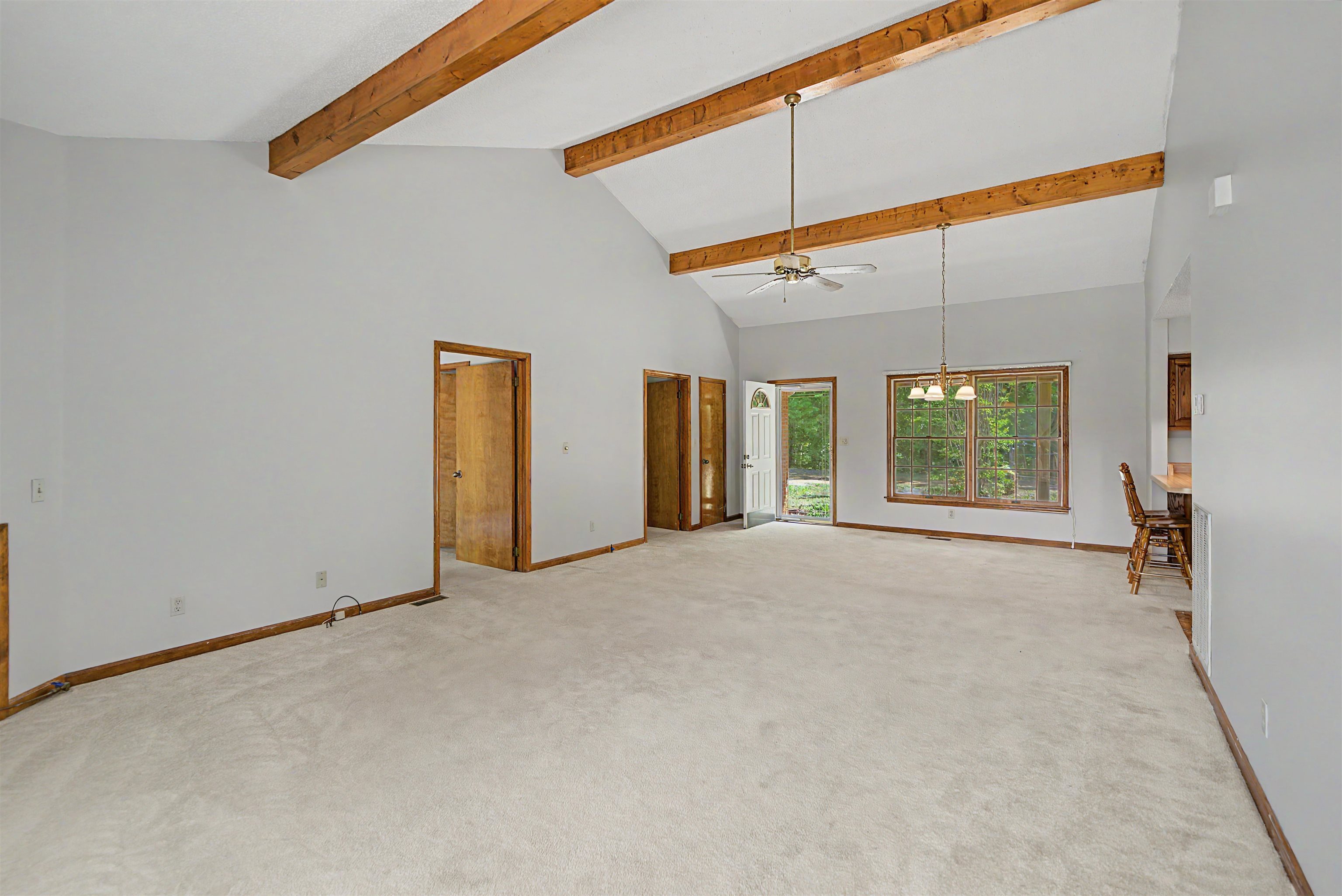 162 Lawton Road Selmer, TN 38375 - Photo 12 of 36 Spacious living area featuring a vaulted ceiling with exposed wood beams, neutral carpeting, and light gray walls