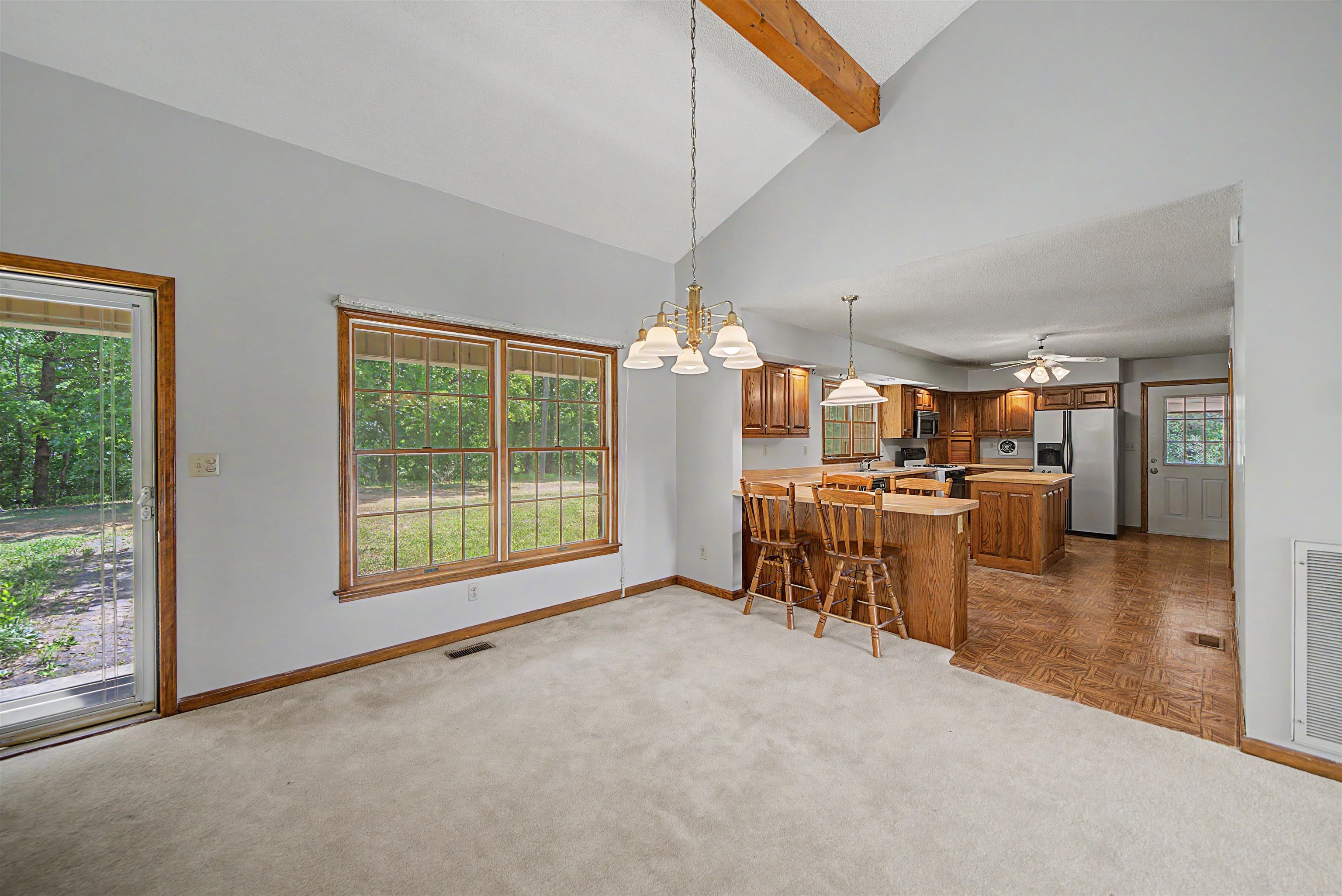 162 Lawton Road Selmer, TN 38375 - Photo 13 of 36 Vaulted ceiling with exposed wood beam and a chandelier over carpeted flooring