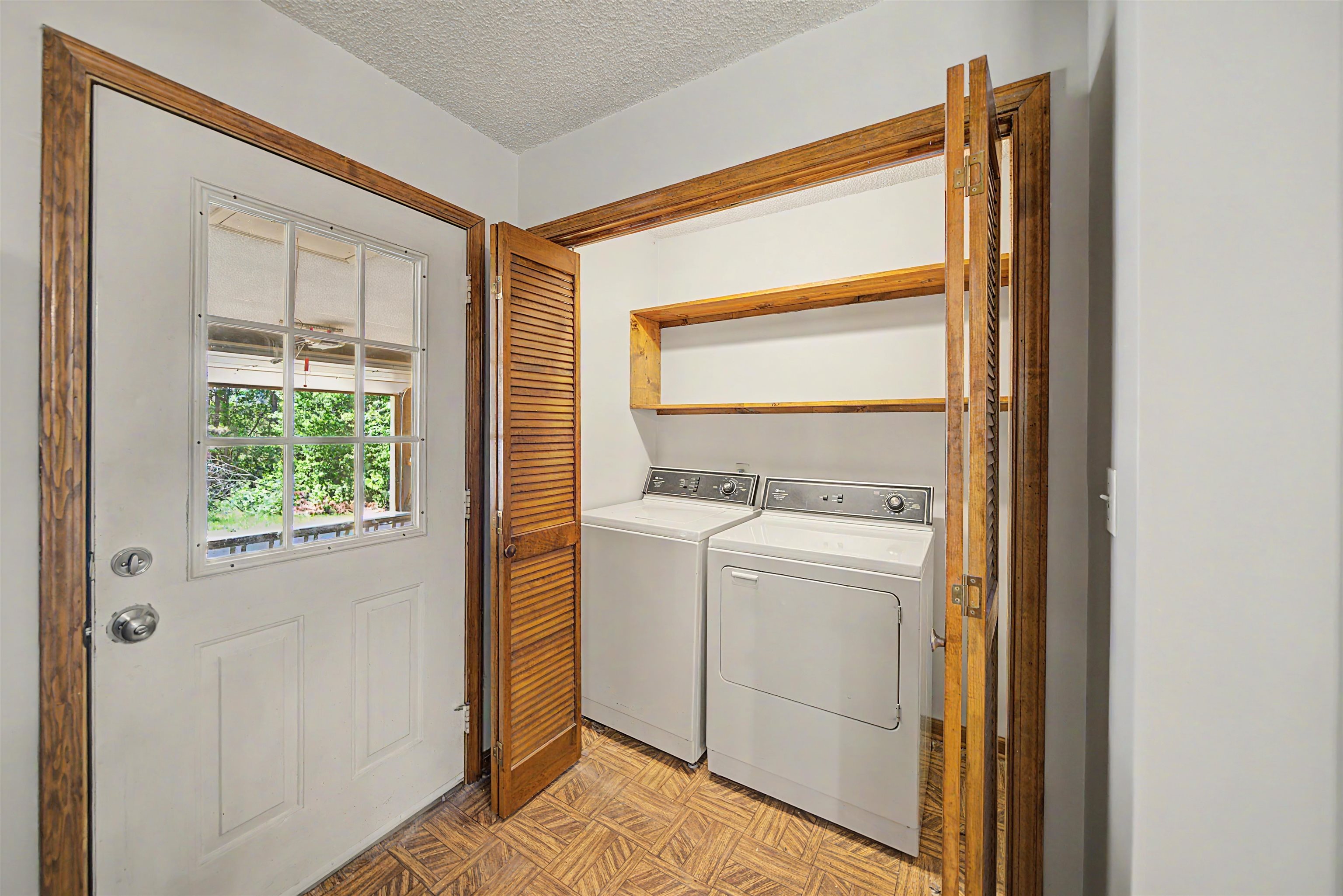 162 Lawton Road Selmer, TN 38375 - Photo 18 of 36 Dedicated laundry area featuring a washer and dryer, wood-finish shelving, and bi-fold louvered doors