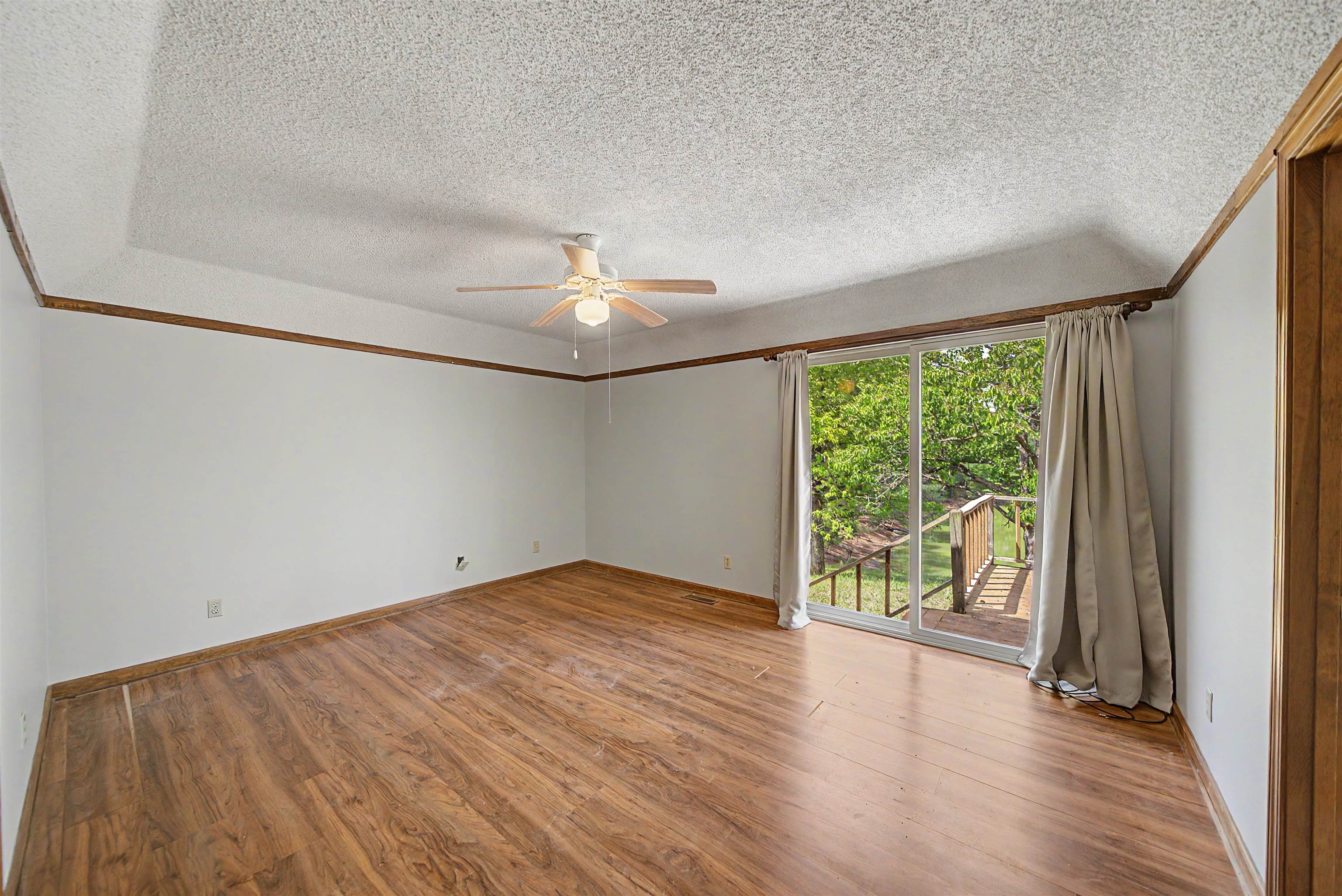 162 Lawton Road Selmer, TN 38375 - Photo 19 of 36 Spacious room featuring wood-finish flooring, white walls with wood trim, and a tray ceiling
