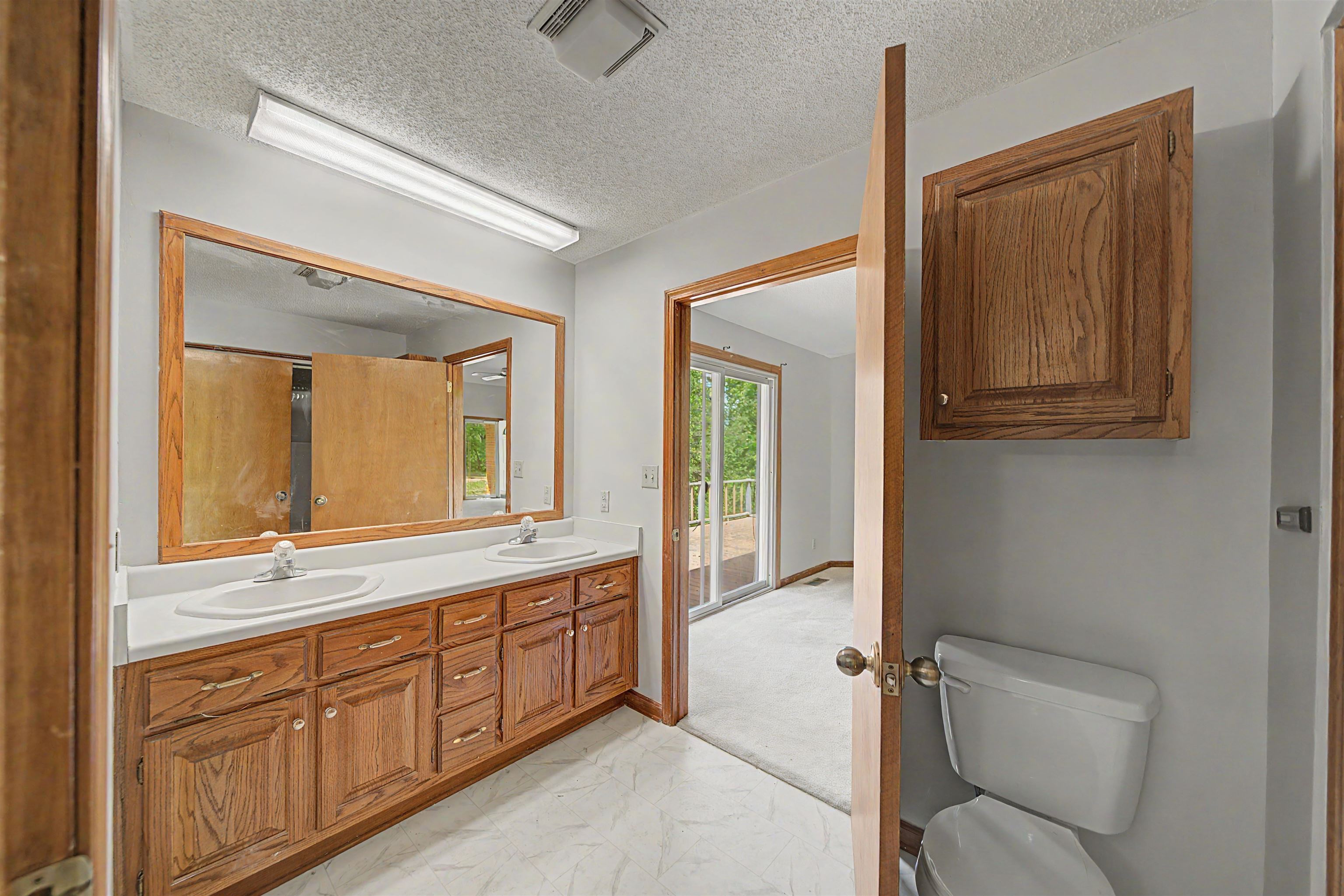 162 Lawton Road Selmer, TN 38375 - Photo 20 of 36 Bathroom featuring a dual vanity with oak cabinetry, white countertops, and a large wall-mounted mirror