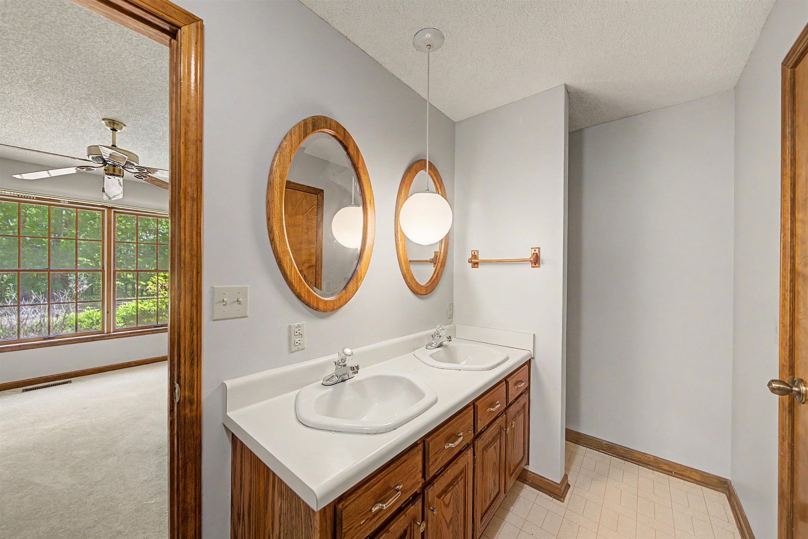 162 Lawton Road Selmer, TN 38375 - Photo 24 of 36 Bathroom featuring a double vanity with white countertops, oval mirrors with wood frames, and wood-finish cabinetry