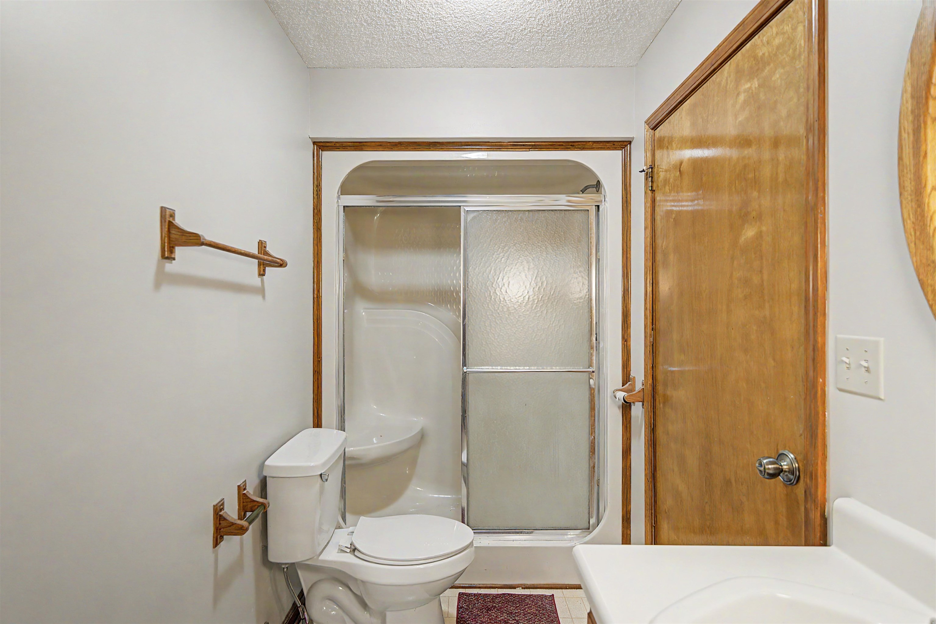 162 Lawton Road Selmer, TN 38375 - Photo 25 of 36 Bathroom featuring a white toilet, enclosed shower with frosted glass, wood-finish trim, and a built-in vanity with a basin sink
