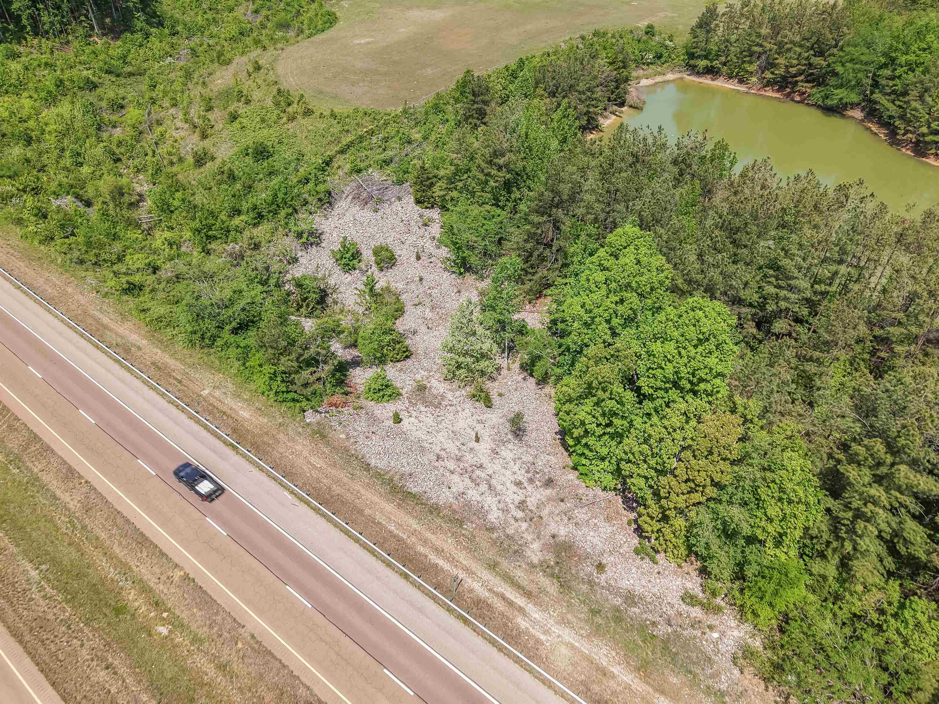 162 Lawton Road Selmer, TN 38375 - Photo 26 of 36 Expansive land parcel featuring a visible roadway, dense tree coverage, and a natural pond
