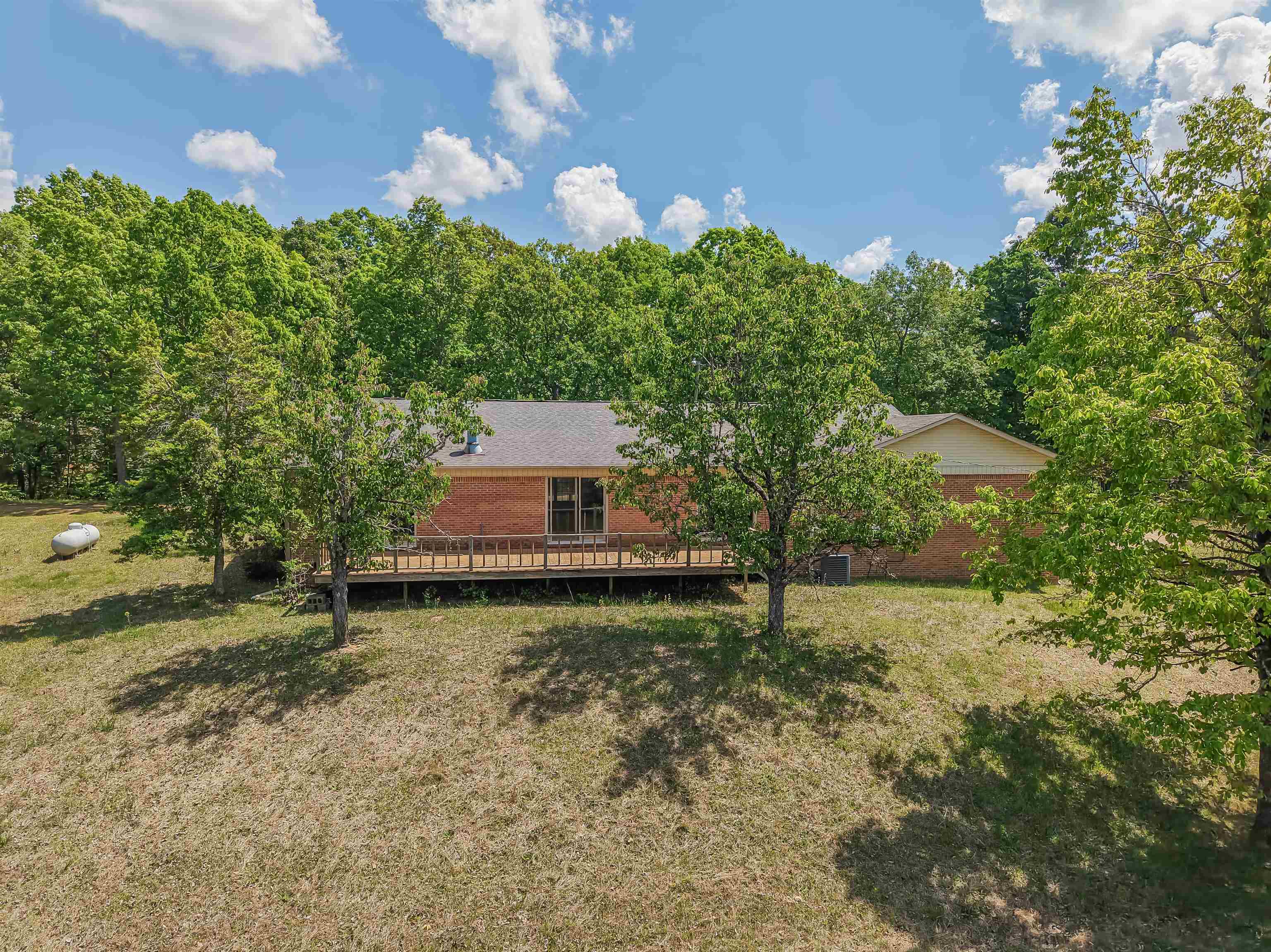 162 Lawton Road Selmer, TN 38375 - Photo 3 of 36 Brick exterior home with a back deck, surrounded by mature trees and natural landscaping