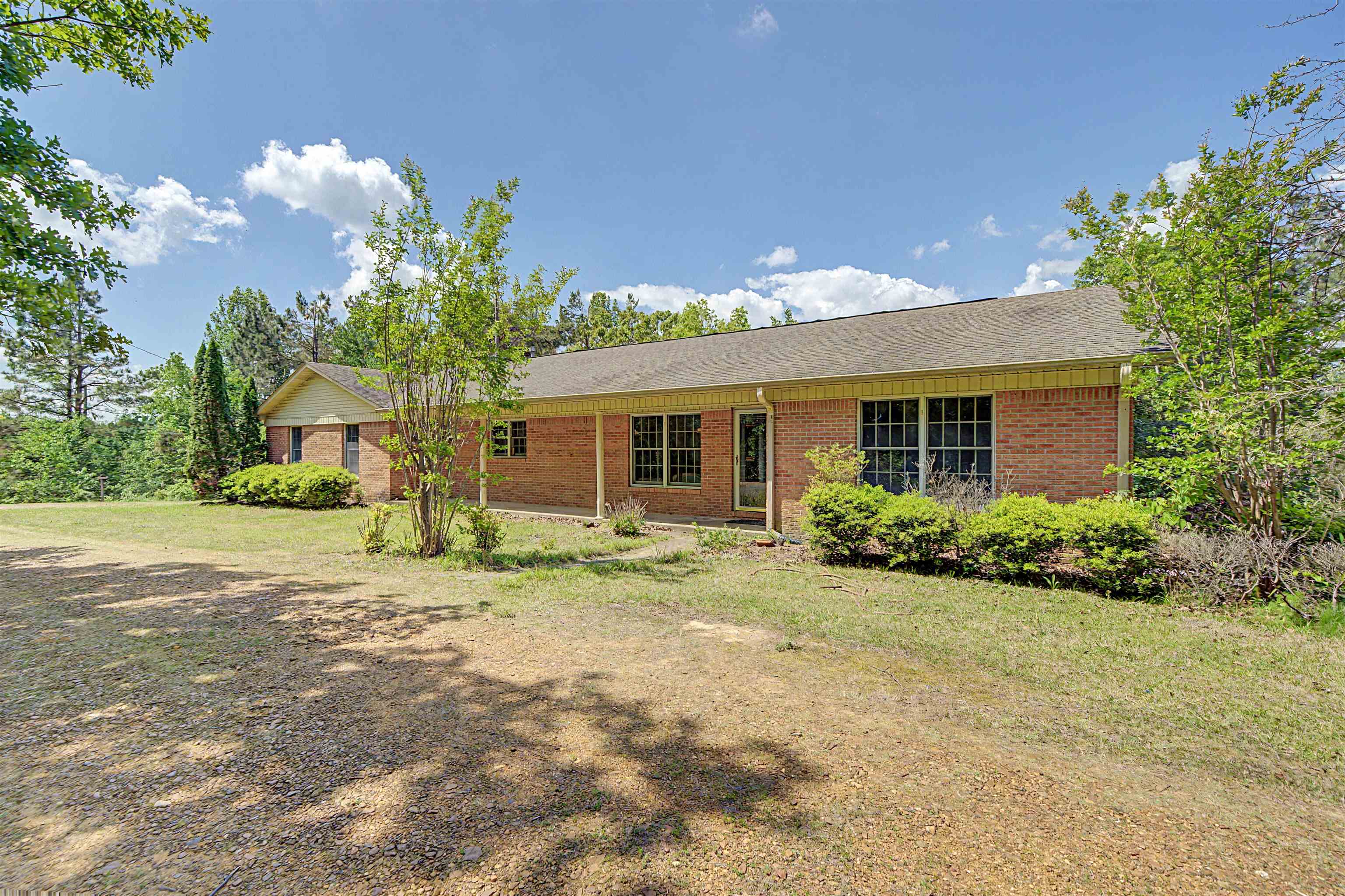 162 Lawton Road Selmer, TN 38375 - Photo 7 of 36 Brick exterior featuring a covered front porch, multiple windows, and surrounding mature trees