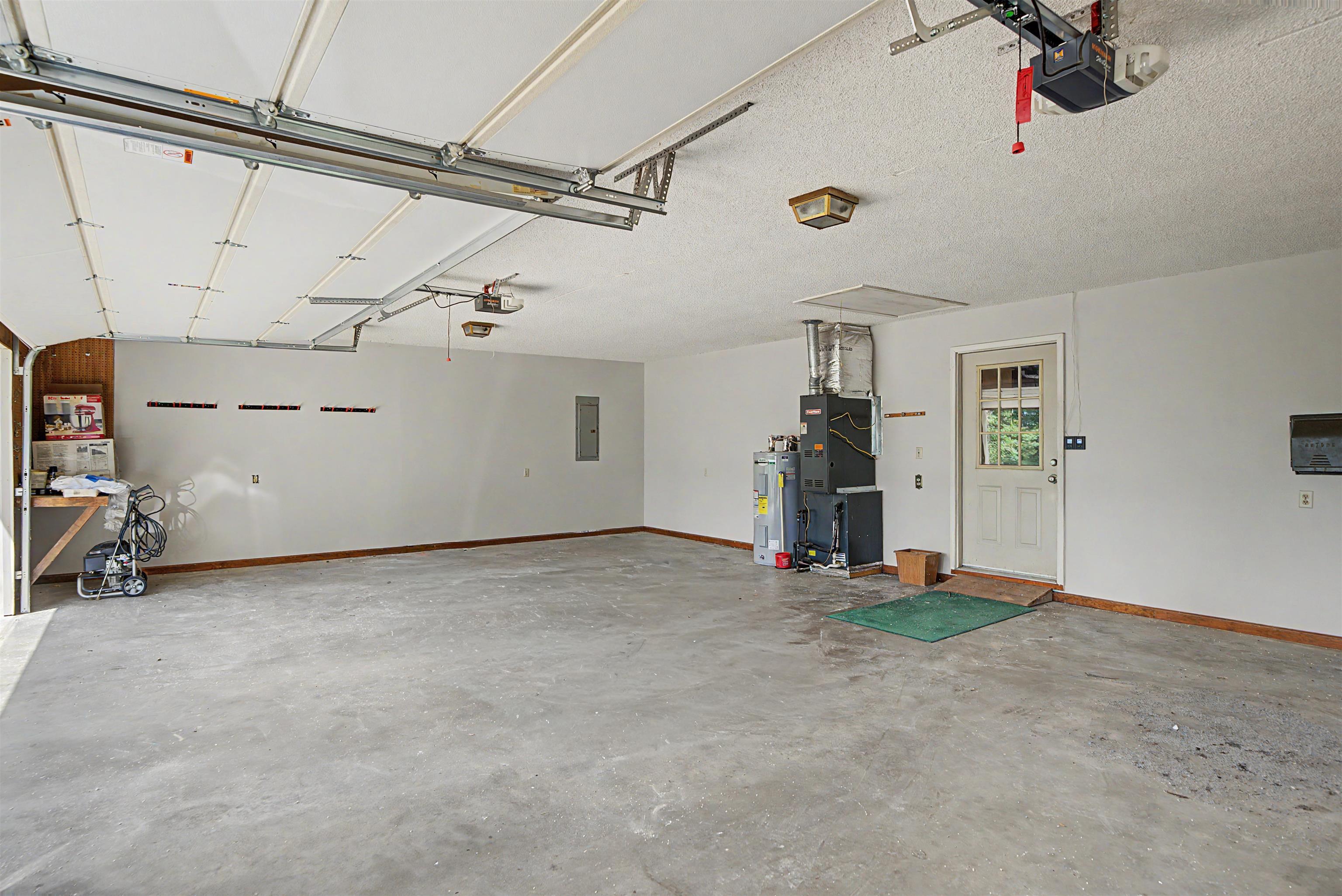 162 Lawton Road Selmer, TN 38375 - Photo 9 of 36 Spacious garage featuring a concrete floor, white walls, exposed ceiling joists, an interior access door, and a built-in workbench