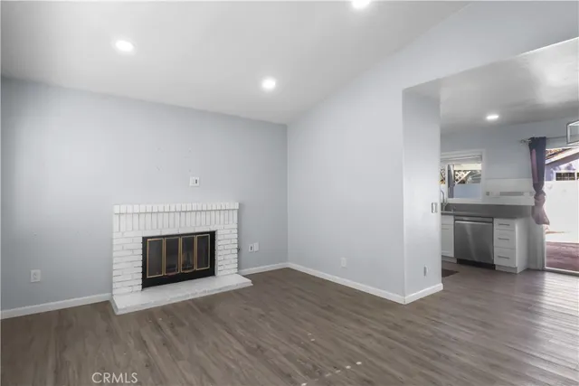 a view of empty room with kitchen and fireplace